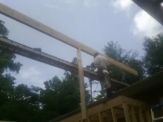 Carpenter setting a ridge beam over a new addition frame — Ice Dam Removal by Roofing Brothers in Smithfield
